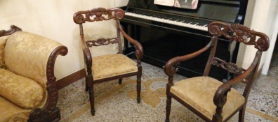 Un salottino due poltroncine e alle spalle un pianoforte, location per degli incontri